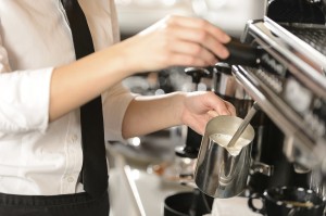 Barista steaming milk for hot cappuccino